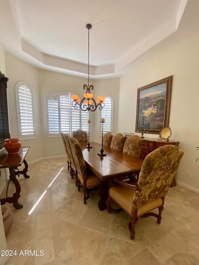 dining area with a raised ceiling and an inviting chandelier