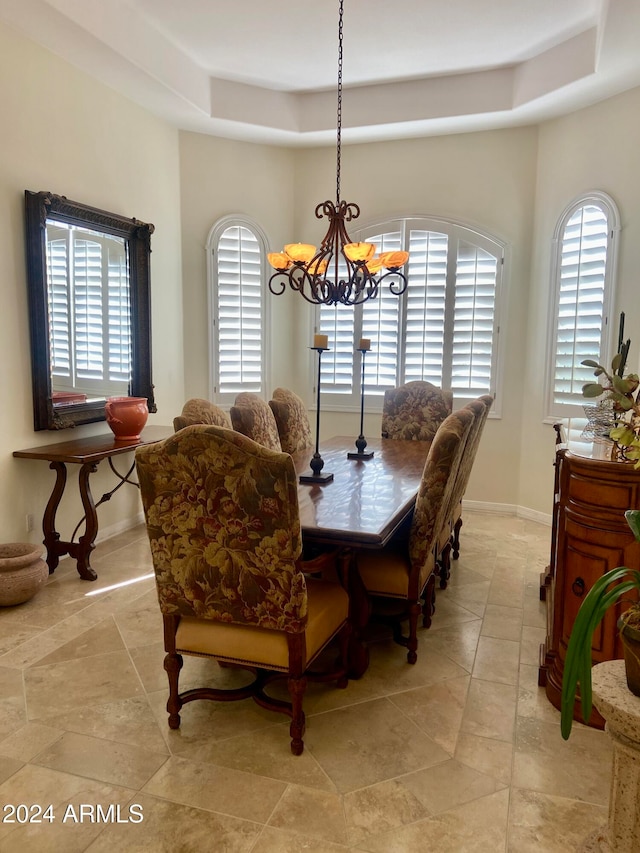 dining area with a notable chandelier and a raised ceiling