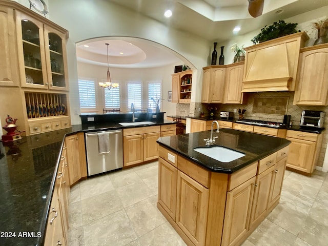 kitchen with a kitchen island with sink, a raised ceiling, sink, and appliances with stainless steel finishes