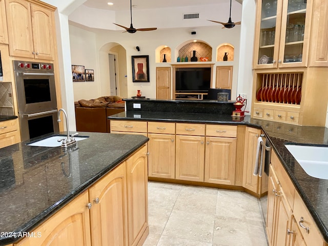 kitchen featuring sink, light brown cabinets, dark stone countertops, and stainless steel appliances