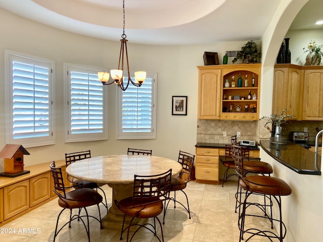 tiled dining space featuring a tray ceiling and a chandelier