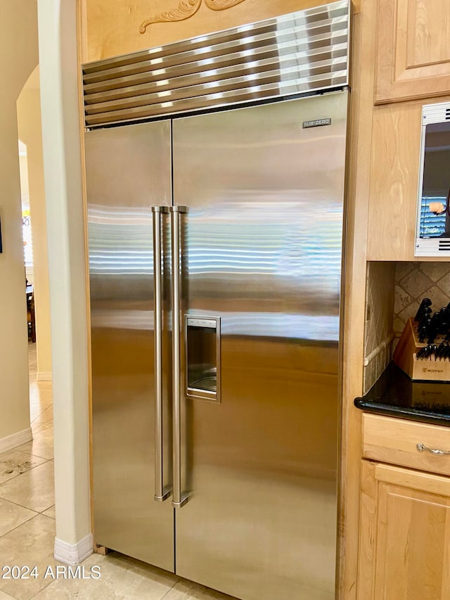 interior details featuring decorative backsplash, built in refrigerator, light brown cabinetry, and light tile patterned floors