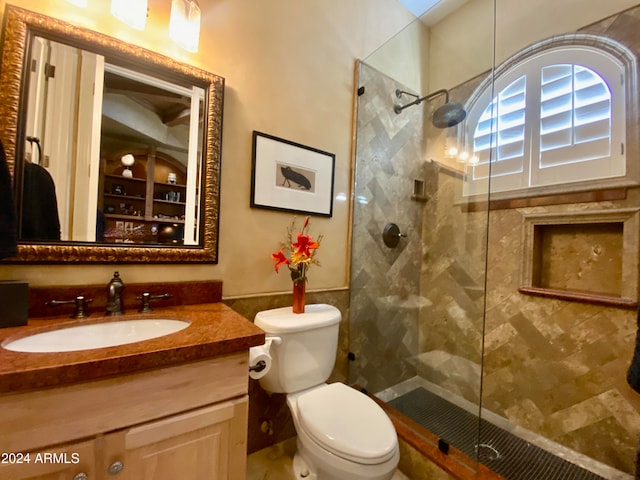 bathroom with tiled shower, vanity, and toilet