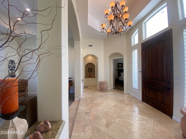 entryway with a towering ceiling and a chandelier