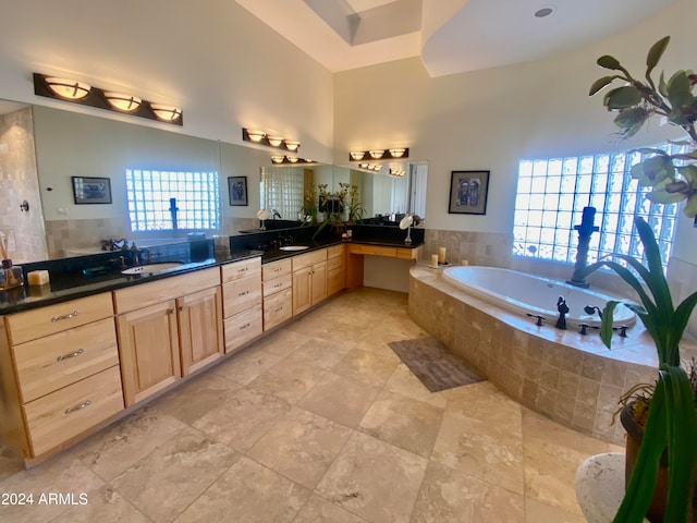 bathroom with tiled tub, plenty of natural light, and vanity