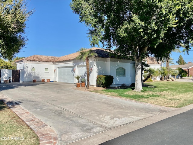 mediterranean / spanish house featuring a garage and a front lawn