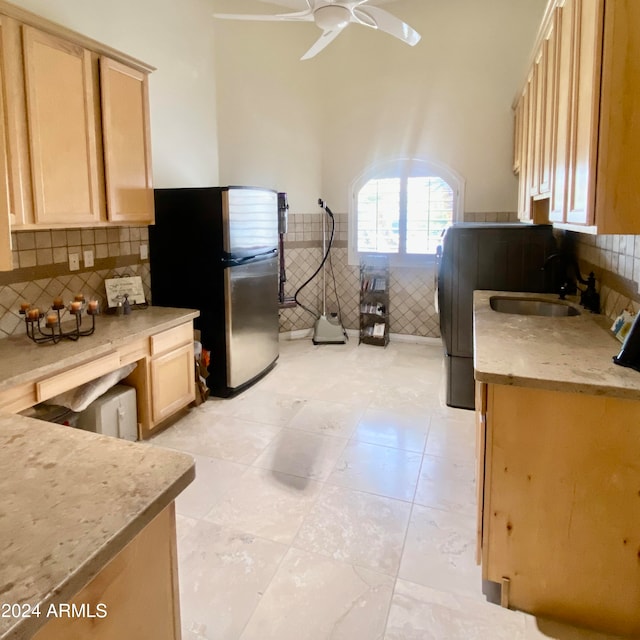 kitchen with stainless steel fridge, ceiling fan, light brown cabinetry, and sink