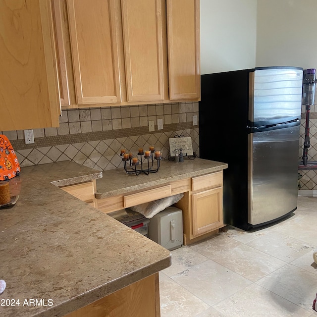 kitchen with decorative backsplash, stainless steel fridge, and light brown cabinets