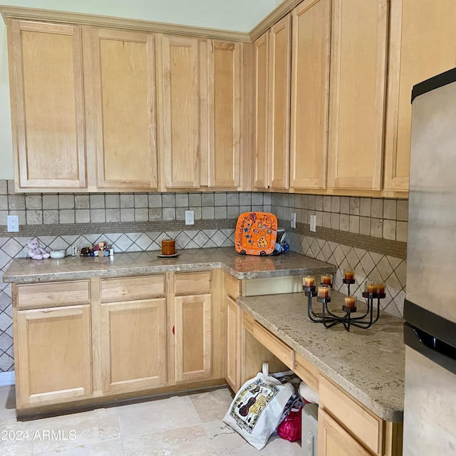 kitchen with decorative backsplash, stainless steel fridge, light stone countertops, and light brown cabinets