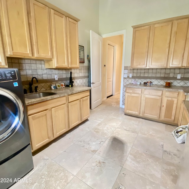 kitchen with light brown cabinetry, backsplash, washer / clothes dryer, and sink