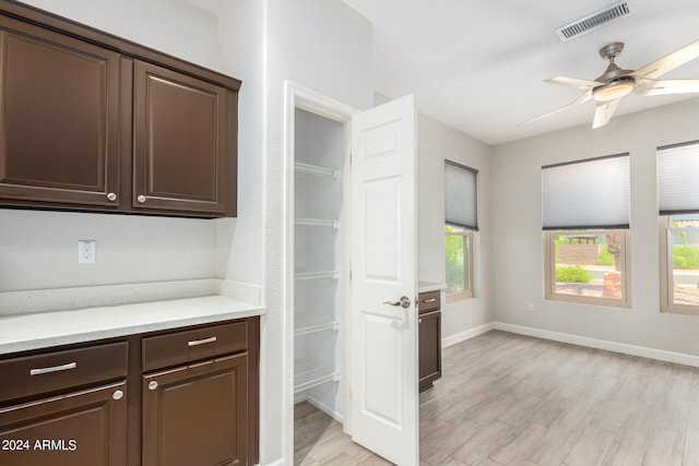 interior space featuring light hardwood / wood-style flooring, light stone countertops, ceiling fan, and dark brown cabinets