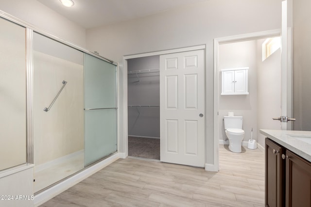 bathroom with vanity, walk in shower, wood-type flooring, and toilet