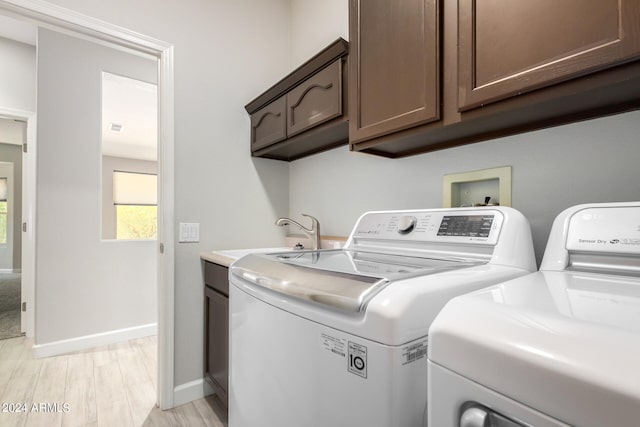 washroom featuring sink, cabinets, light wood-type flooring, and separate washer and dryer