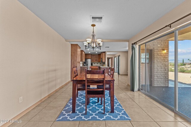 dining room featuring a chandelier, a textured ceiling, and light tile patterned flooring