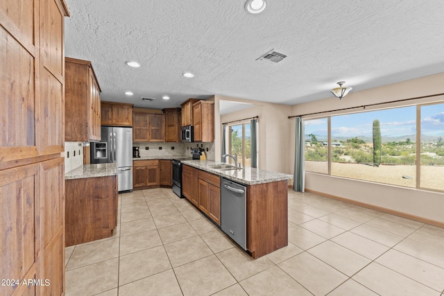 kitchen with light stone counters, light tile patterned flooring, sink, backsplash, and appliances with stainless steel finishes