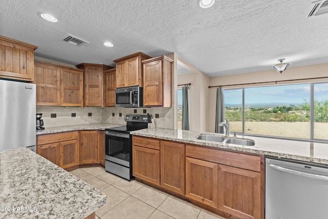 kitchen with a textured ceiling, sink, decorative backsplash, appliances with stainless steel finishes, and light tile patterned floors