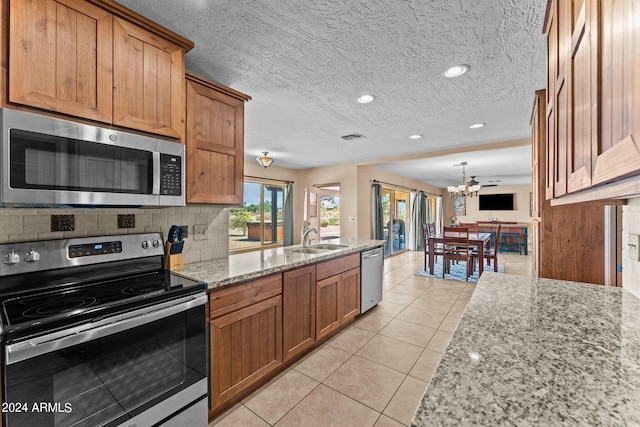 kitchen featuring appliances with stainless steel finishes, light tile patterned flooring, backsplash, light stone countertops, and sink