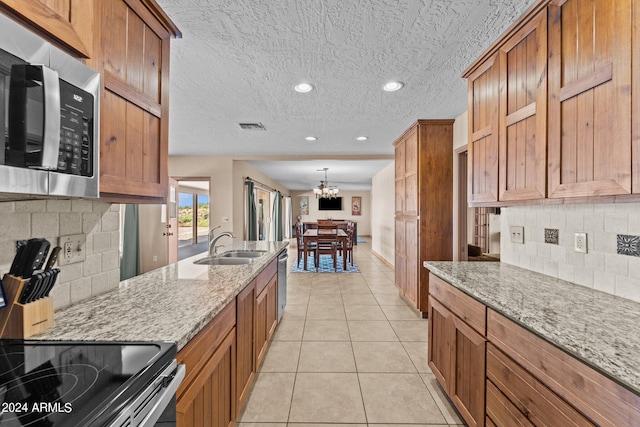 kitchen featuring decorative backsplash, light stone counters, appliances with stainless steel finishes, and a chandelier