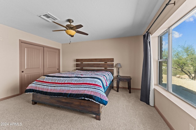 bedroom featuring light carpet, ceiling fan, and a closet