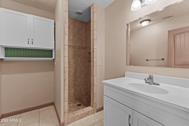 bathroom featuring vanity, a tile shower, a textured ceiling, and tile patterned floors