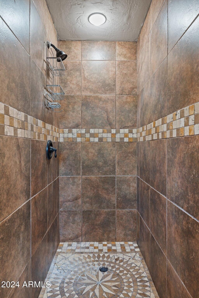 bathroom featuring a textured ceiling and a tile shower