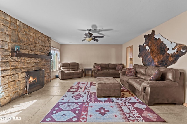 living room with ceiling fan, light tile patterned flooring, and a stone fireplace