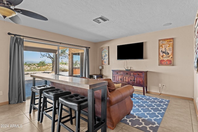 tiled living room featuring ceiling fan and a textured ceiling