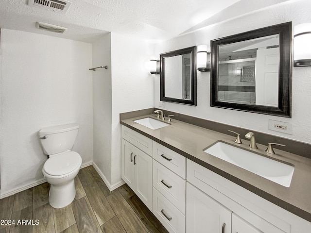 bathroom with walk in shower, vanity, a textured ceiling, wood-type flooring, and toilet