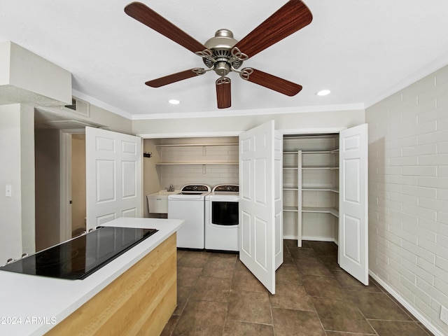 laundry room with brick wall, ceiling fan, crown molding, sink, and washing machine and clothes dryer