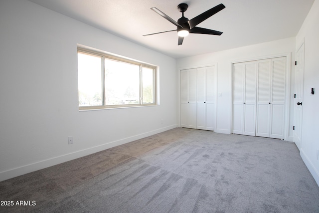 unfurnished bedroom featuring carpet floors, two closets, a ceiling fan, and baseboards