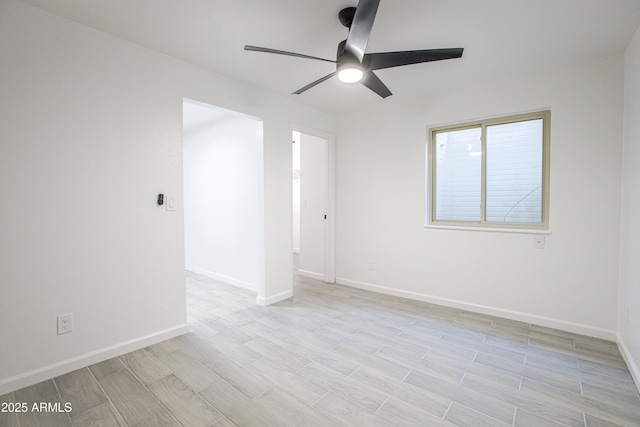 spare room with ceiling fan, light wood-style flooring, and baseboards