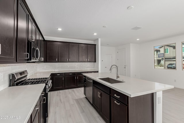 kitchen with tasteful backsplash, appliances with stainless steel finishes, light countertops, and a sink