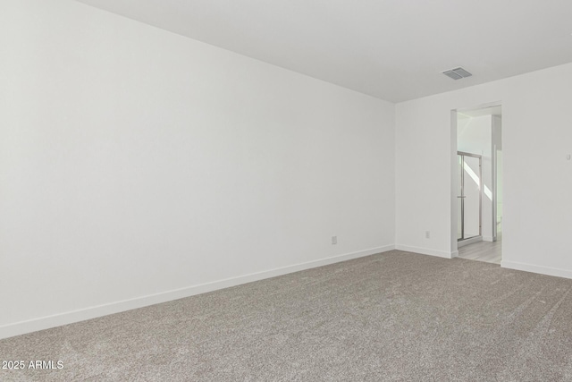 unfurnished room with baseboards, visible vents, and light colored carpet