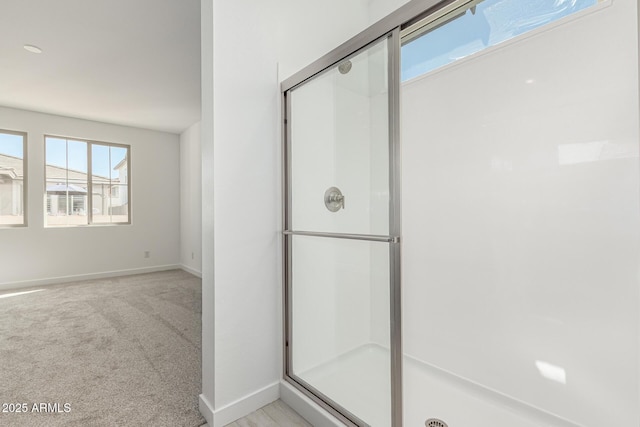 bathroom featuring a shower stall and baseboards