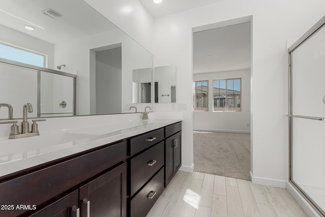 bathroom with double vanity, a stall shower, a sink, and a healthy amount of sunlight