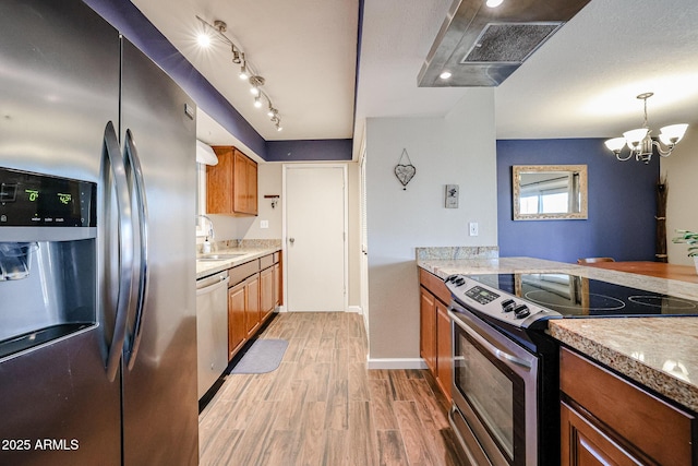 kitchen with light hardwood / wood-style flooring, decorative light fixtures, stainless steel appliances, a notable chandelier, and sink