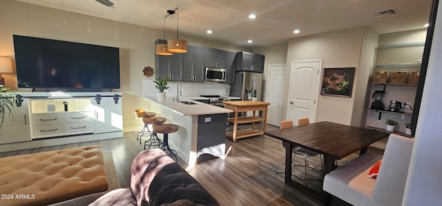 kitchen featuring dark hardwood / wood-style flooring, kitchen peninsula, pendant lighting, a breakfast bar area, and appliances with stainless steel finishes