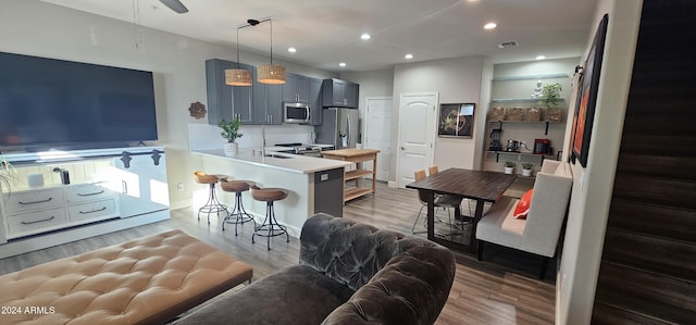 kitchen featuring a breakfast bar area, ceiling fan, light hardwood / wood-style floors, kitchen peninsula, and stainless steel appliances