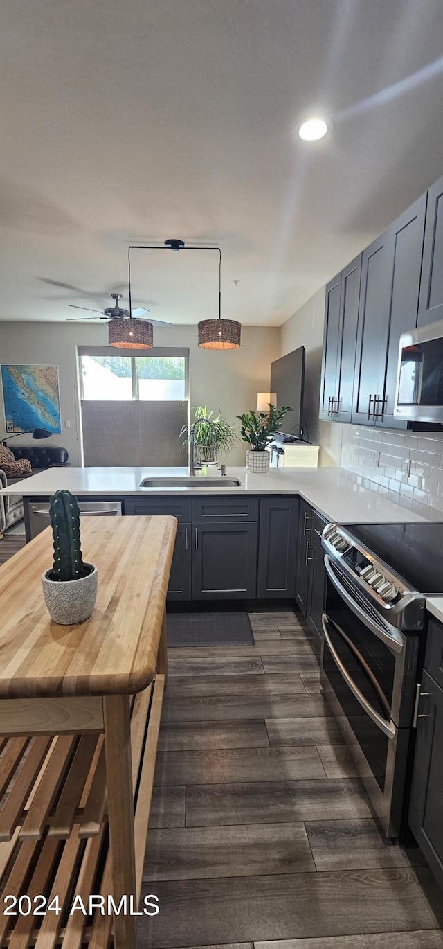 kitchen featuring wooden counters, sink, hanging light fixtures, dark hardwood / wood-style flooring, and stainless steel appliances