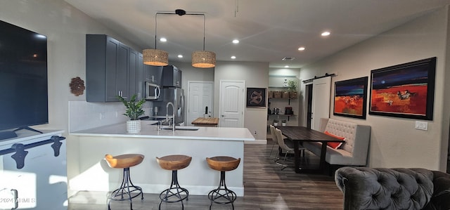 kitchen featuring sink, dark wood-type flooring, a barn door, kitchen peninsula, and pendant lighting