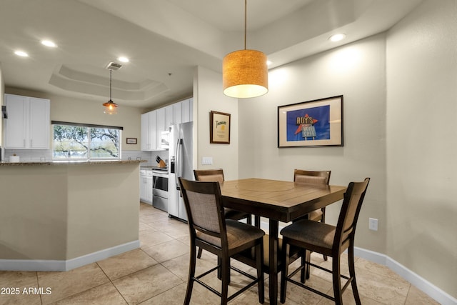 dining area with light tile patterned flooring and a tray ceiling