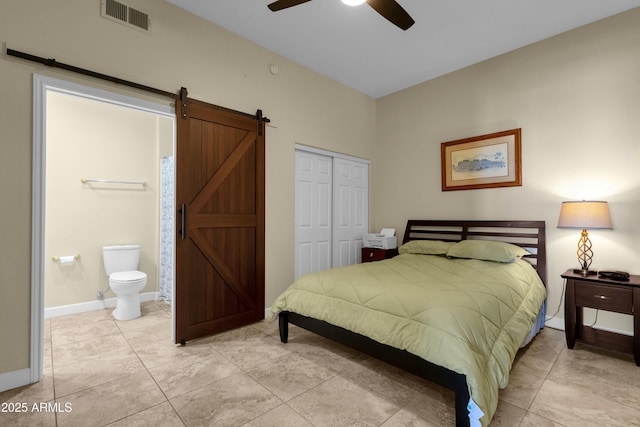 tiled bedroom with ceiling fan, ensuite bathroom, a barn door, and a closet