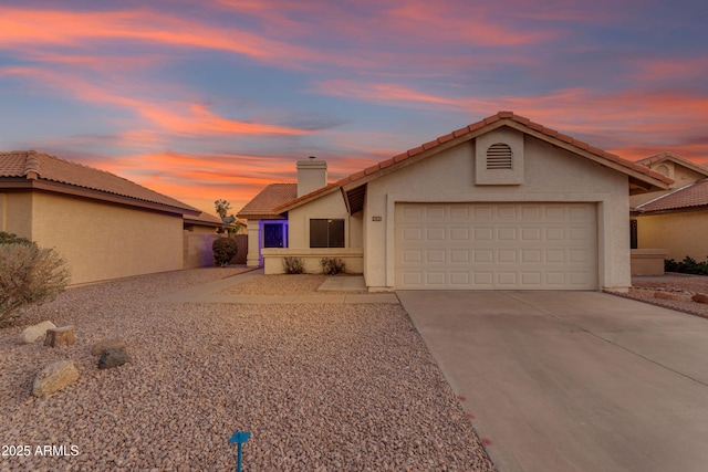 view of front of property with a garage, a tiled roof, concrete driveway, and stucco siding