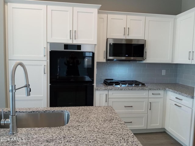 kitchen featuring sink, stainless steel appliances, backsplash, white cabinets, and hardwood / wood-style flooring