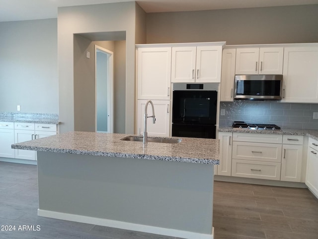 kitchen featuring stainless steel appliances, white cabinetry, a center island with sink, and sink