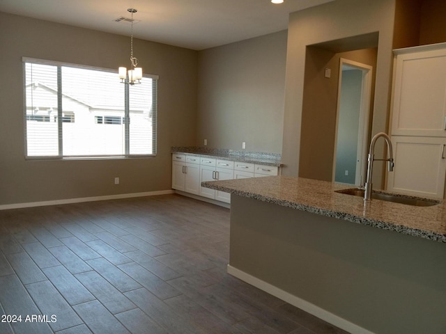 kitchen featuring white cabinetry, sink, pendant lighting, and wood-type flooring