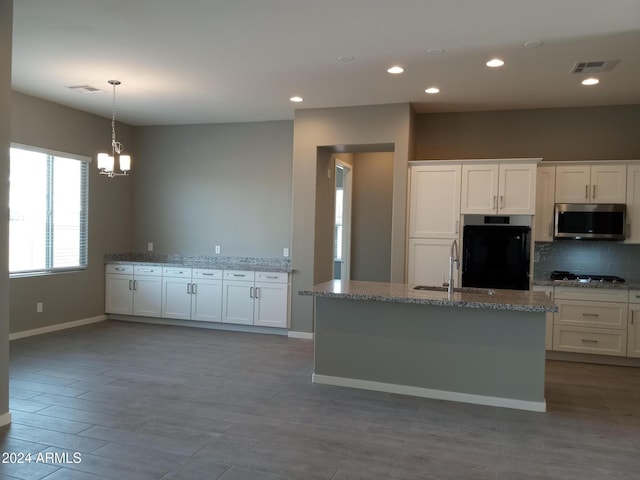 kitchen with a center island with sink, white cabinetry, and sink