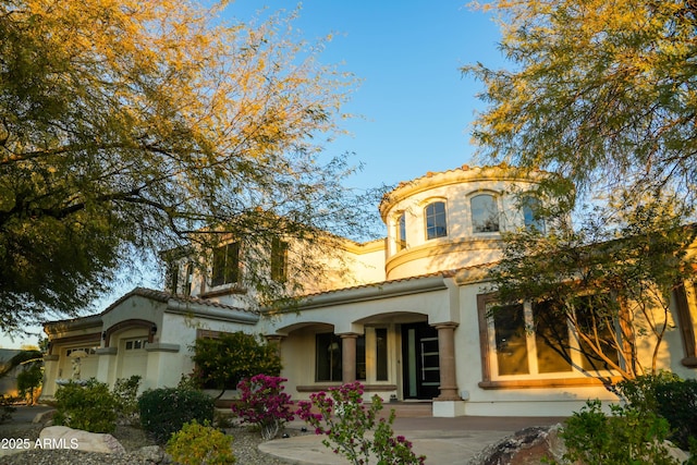 mediterranean / spanish house featuring a tiled roof and stucco siding