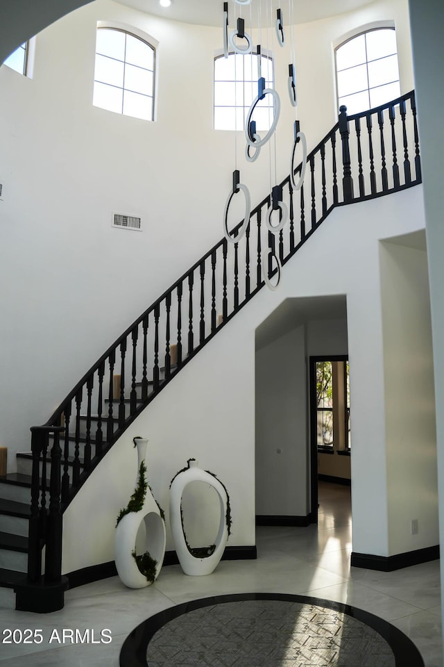 stairs featuring baseboards, visible vents, and a high ceiling