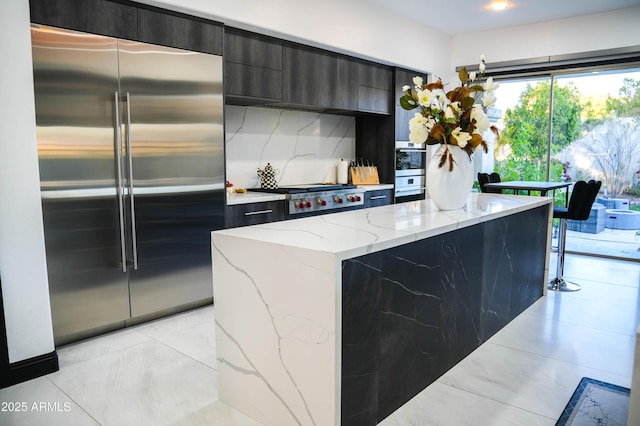 kitchen with light stone counters, light tile patterned floors, decorative backsplash, appliances with stainless steel finishes, and modern cabinets